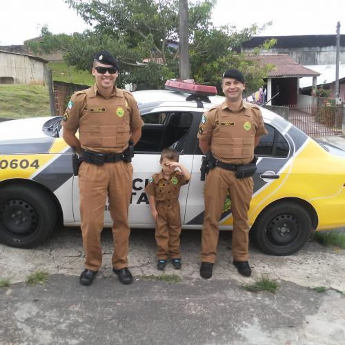 Policiais militares entregam farda infantil para criança em Campo Largo, na RMC