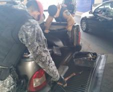 Policiais militares vistoriando veículo com fundo falso.