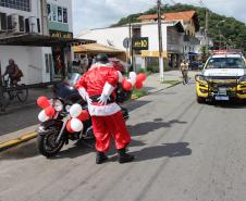 PM promove ação de Natal e encanta veranistas com entrega de doces e pintura de rosto em Guaratuba (PR), no Litoral do estado
