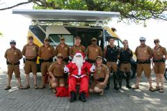 PM promove ação de Natal e encanta veranistas com entrega de doces e pintura de rosto em Guaratuba (PR), no Litoral do estado
