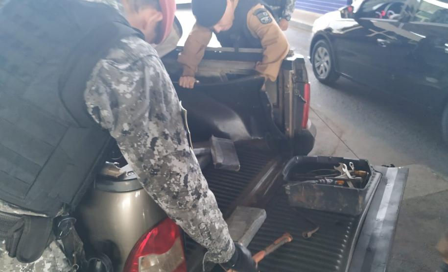 Policiais militares vistoriando veículo com fundo falso.