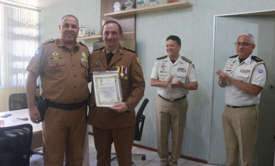 O comandante-geral da Polícia Militar do Paraná, Coronel Hudson Leôncio Teixeira, recebeu nesta sexta-feira (18) a visita do subcomandante-geral da Polícia Militar da Bahia, Coronel Nilton Cezar Machado Espíndola, de forma a debaterem parcerias e troca de experiência entre as polícias do Paraná e da Bahia. Além disso, o Batalhão de Polícia Ambiental Força Verde homenageou o Coronel Nilton Cezar Machado Espíndola com a entrega da medalha do Batalhão Ambiental, devido as contribuições, troca de conhecimentos